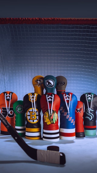 Hometown Brands official NHL headcover collection featuring all US teams. Headcover group featuring Blackhawks, Rangers, Bruins, Stars, Capitals, Kraken, flyers, Penguins, Sharks, and Hurricanes on ice in front of a red and white hockey net.